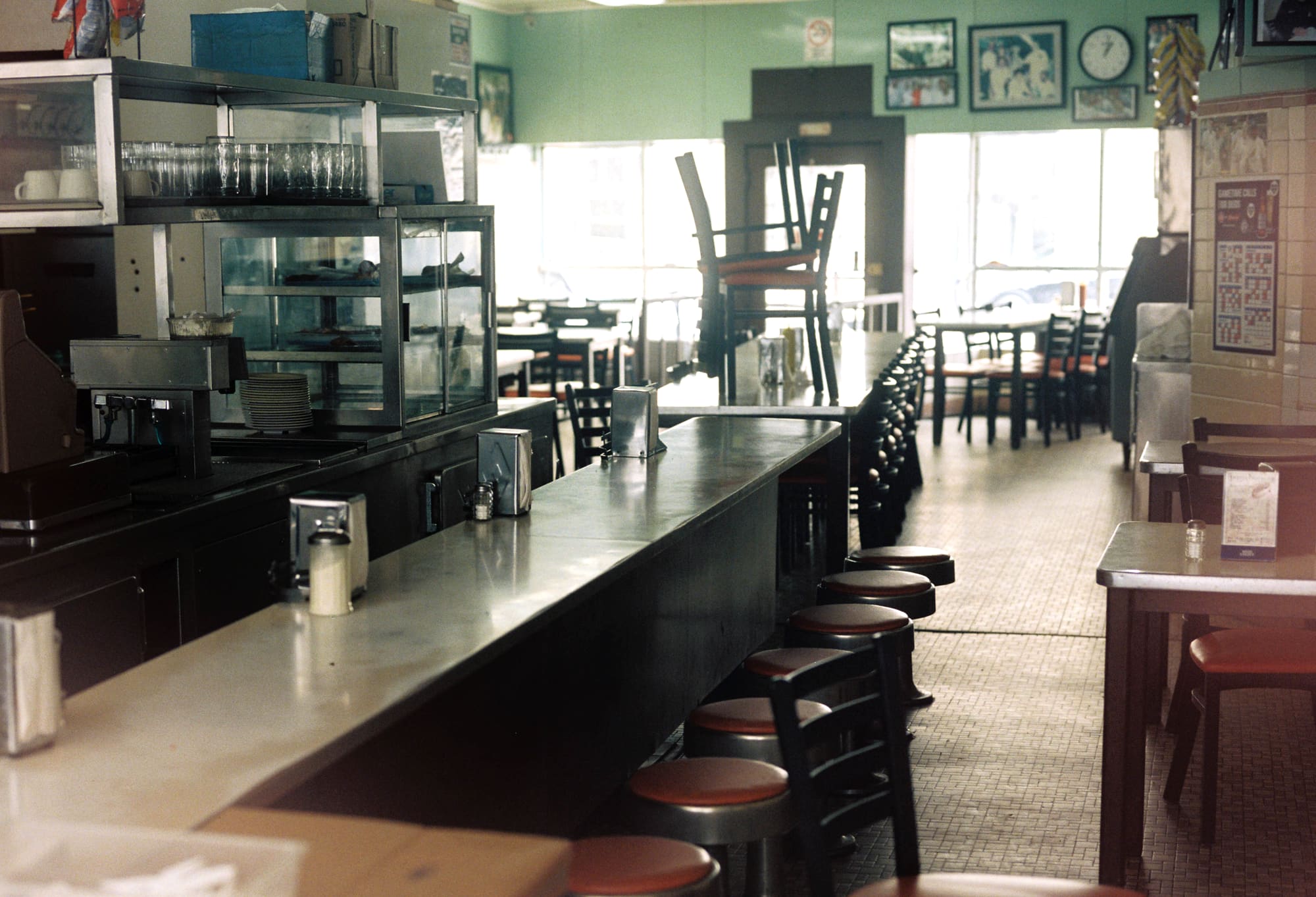 The long counter at Lafayette Coney Island, red-topped stools down one side, mint green walls and framed photographs, daylight coming through the front windows.